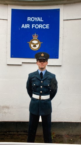 Personnel stands in uniform outside by RAF sign.